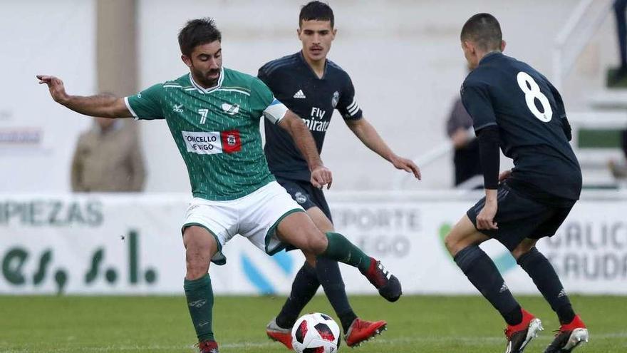 Antón de Vicente, capitán del Coruxo, trata de controlar el balón ante la presencia de dos jugadores del Real Madrid Castilla. // José Lores