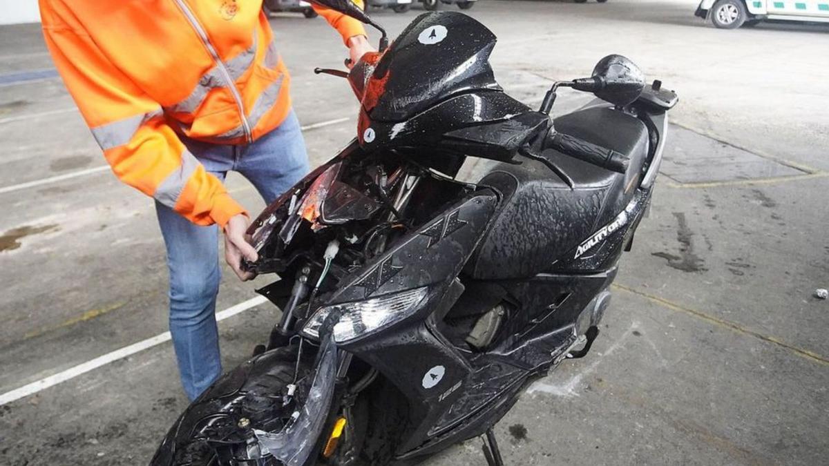 Un empleat de Grues Cruz mostrant la moto sinistrada. | MARC MARTÍ