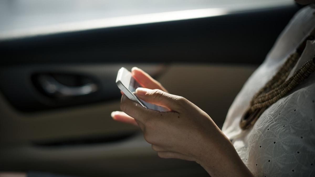 Una mujer con su móvil de copiloto en el coche.