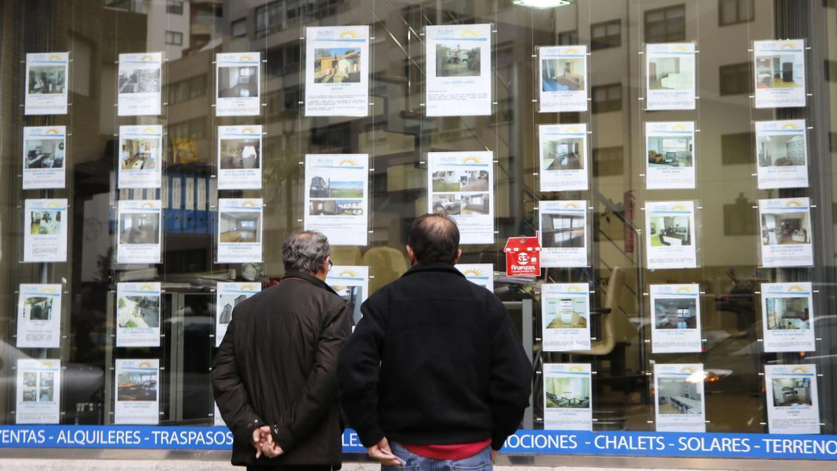 Dos homes consulten anuncis en una agència immobiliària