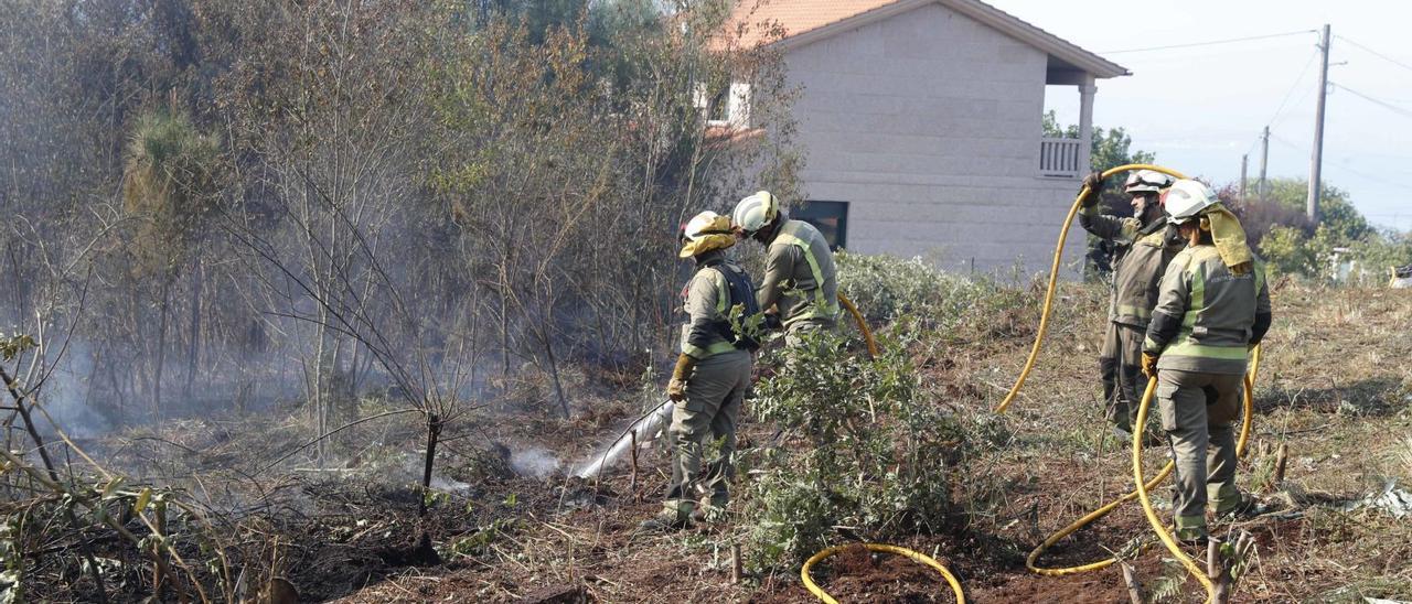 Una brigada enfría el monte de de Meira próximo a casas.   |  FARO