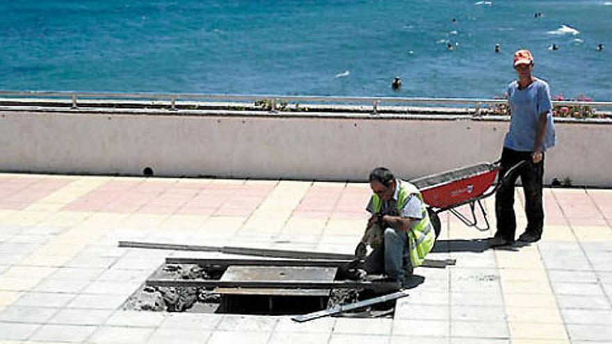 Dos operarios trabajan donde se instalará la escultura en homenaje a las víctimas, con Gando al fondo, ayer.  M.A.M.