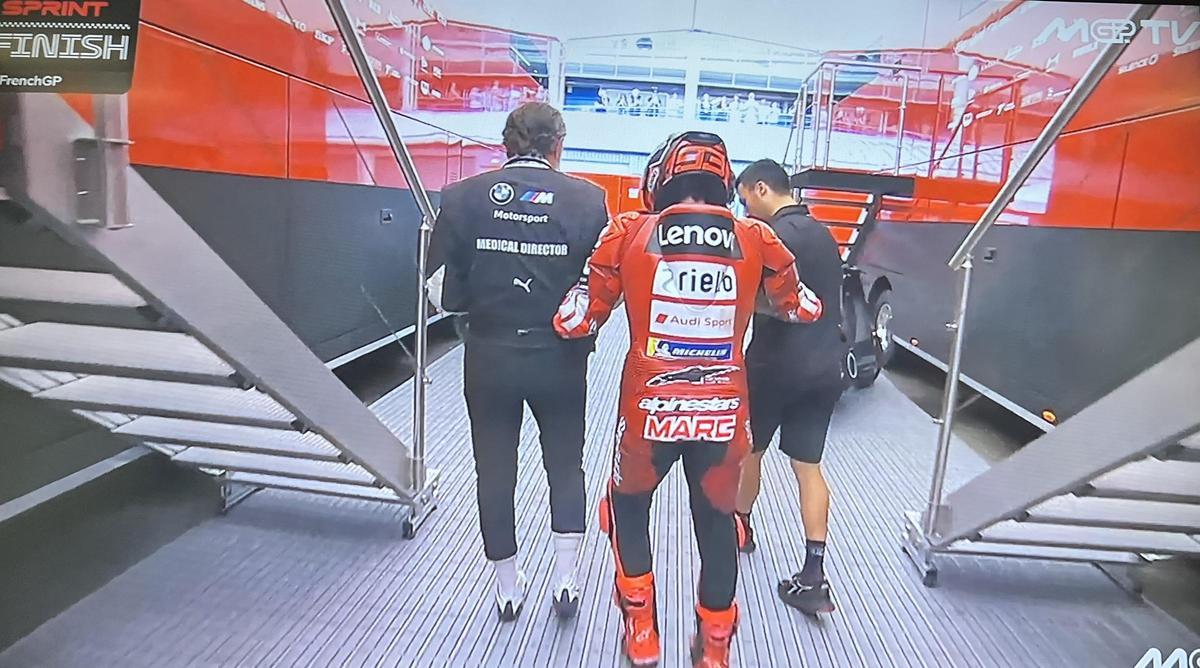 Marc Márquez llega a su camión, ayudado por José Luis Mártinez, su asistente, y el doctor Ángel Charte.