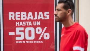 Archivo - Una persona pasa delante de un escaparate durante el comienzo de las rebajas