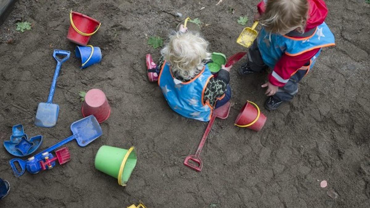 Dos niños juegan con la arena en el patio de una guardería sueca.