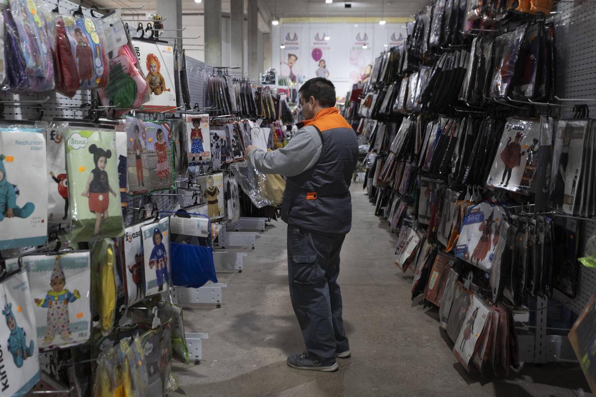 Un padre busca atuendos de carnaval para sus hijos en Ducaval, una tienda de disfraces del Horno de Alcedo afectada por la dana.