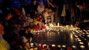 Personas depositan flores y velas en la plaza de Charles Aznavour, en Yerevan, la capital de Armenia.