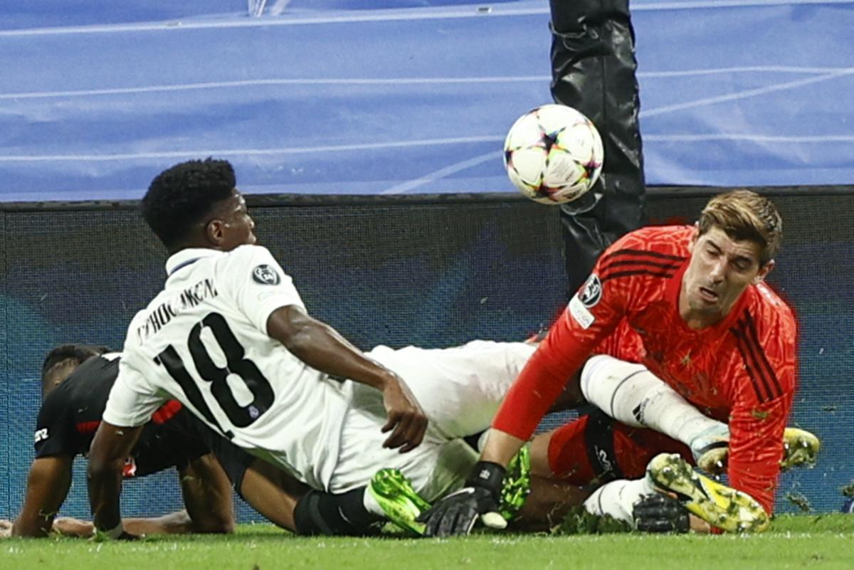Thibaut Courtois y Aurelien Tchouameni pelean un balón con Christopher Nkunku, en un partido de Champions del Real Madrid