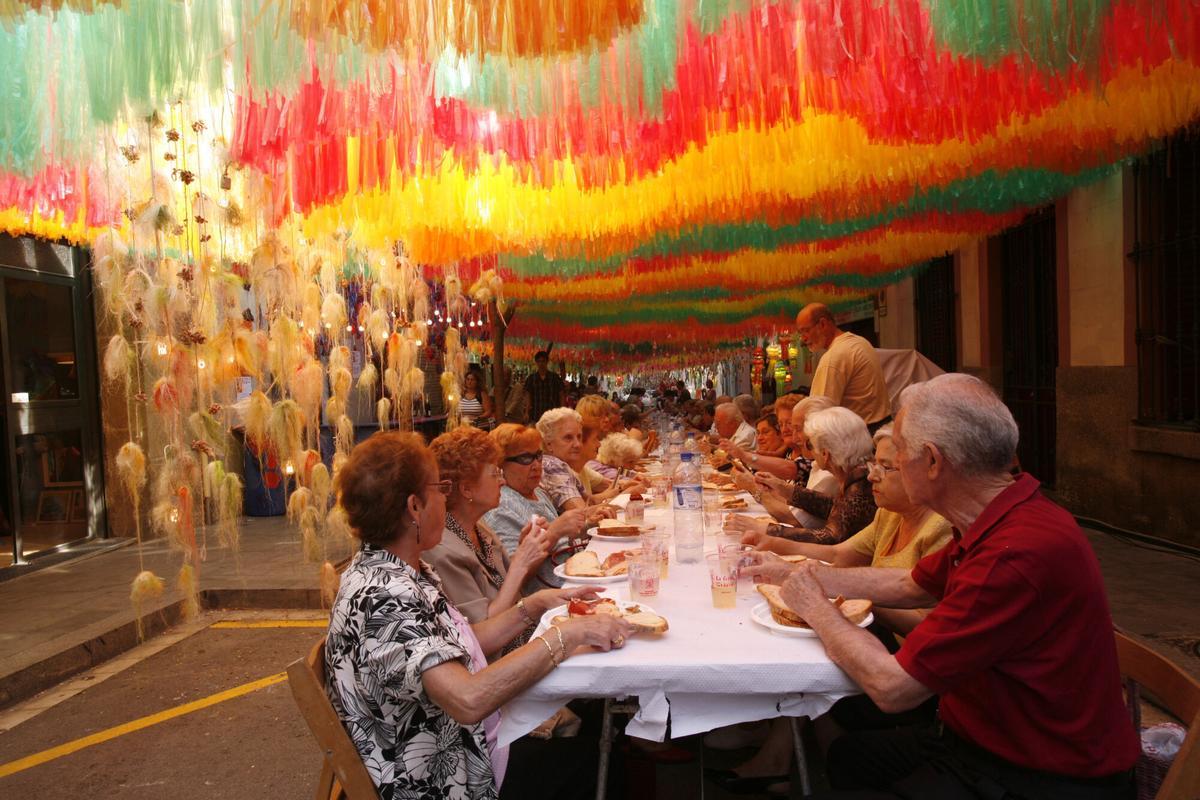 Vecinos en una cena popular en la calle en las fiestas del barrio de Gràcia en Barcelona, en una imagen de archivo, en 2006.