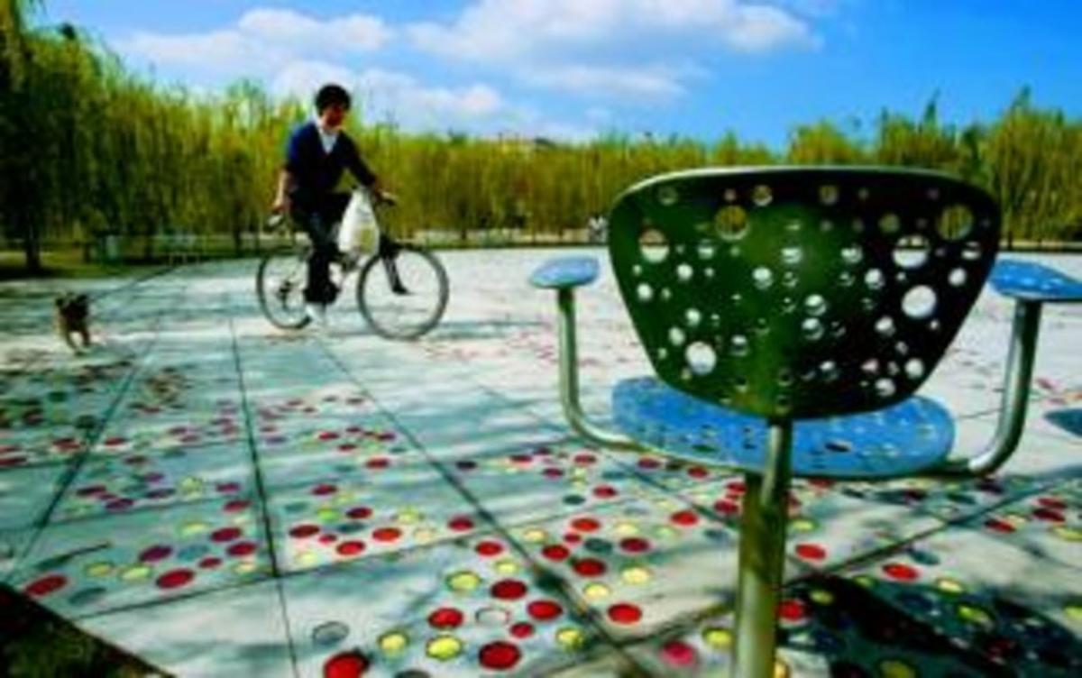 Un ciclista pasea a su perro en el parque del Centre del Poblenou, cerca de una de las criticadas sillas.