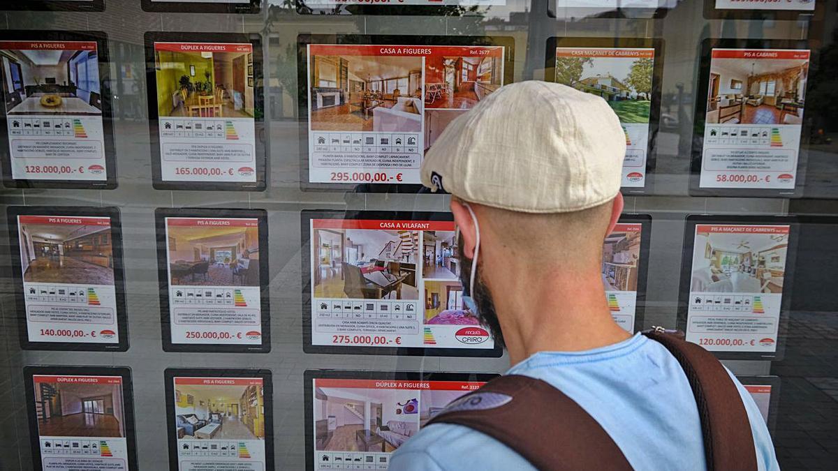 Un jove observa pisos a la venda en una immobiliària a Figueres. | BORJA BALSERA