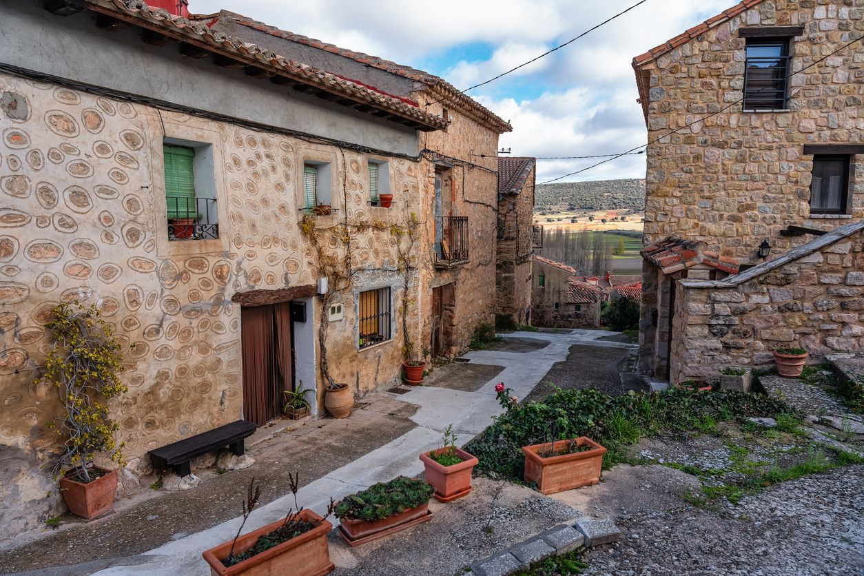 Pintoresca calle con casas de piedra y árboles con hojas caídas en el suelo, Palazuelos.