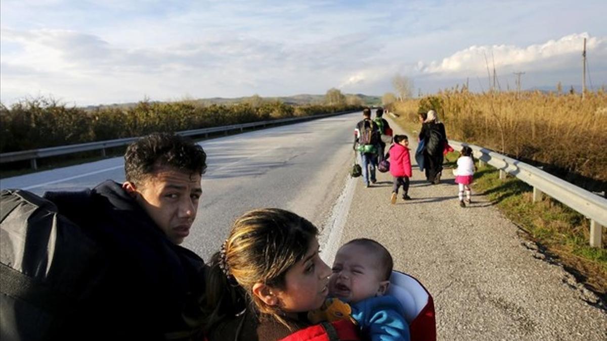 Refugiados llevan a sus hijos a través de una carretera nacional hasta la frontera entre Grecia y Macedonia, cerca de la ciudad griega de Polykastro.