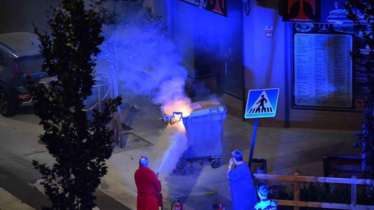 Un vecino sofoca un fuego en un contenedor de basura durante el conflicto laboral de 2024.