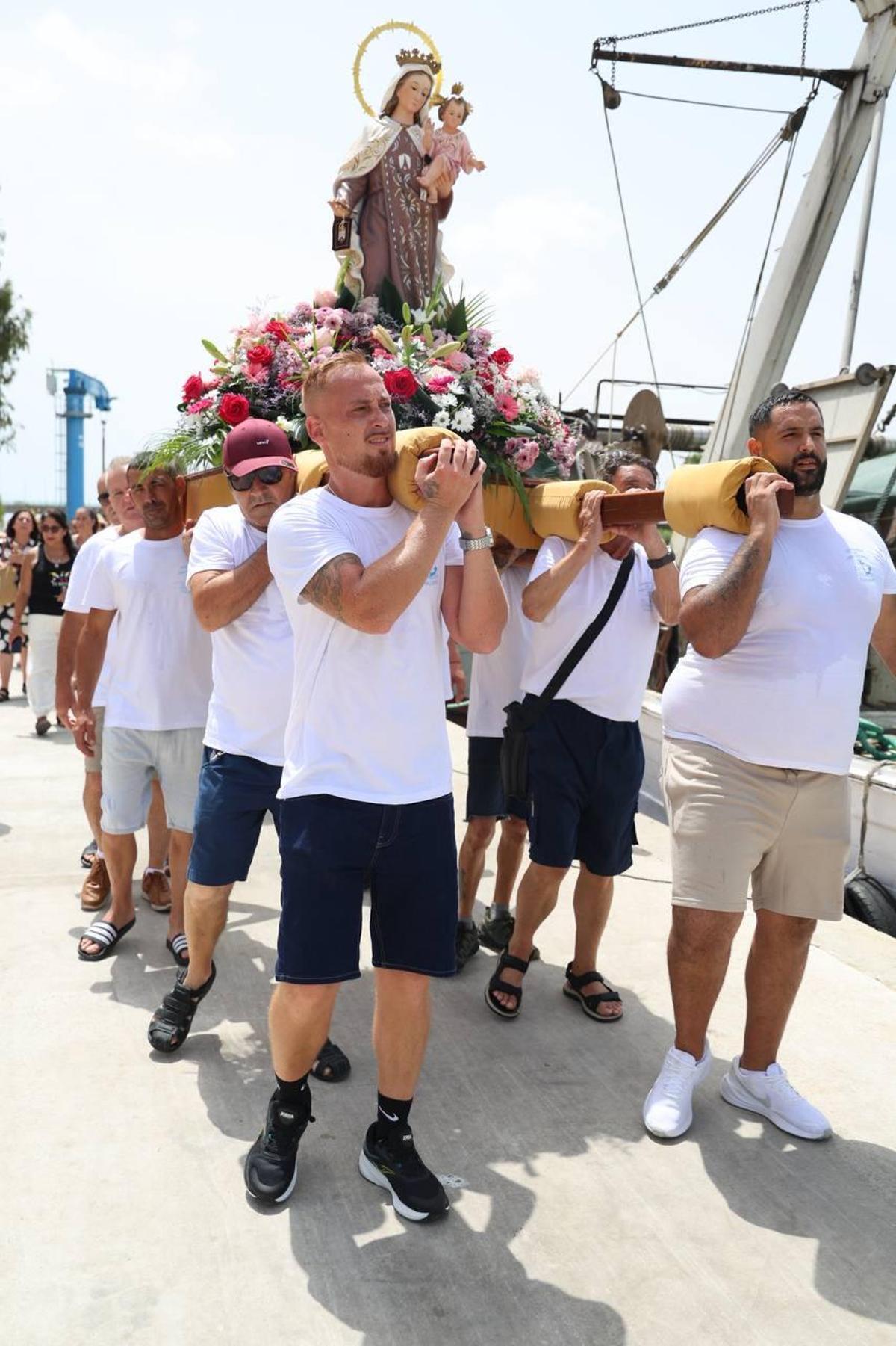 Los pescadores, con la imagen, en su recorrido junto a las embarcaciones amarradas en el puerto.
