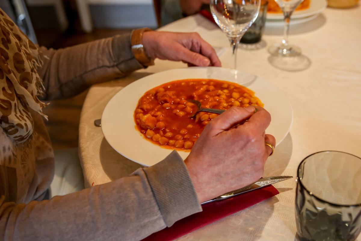 Una comensal se dispone a comer un plato de garbanzos en un restaurante con menú del día.