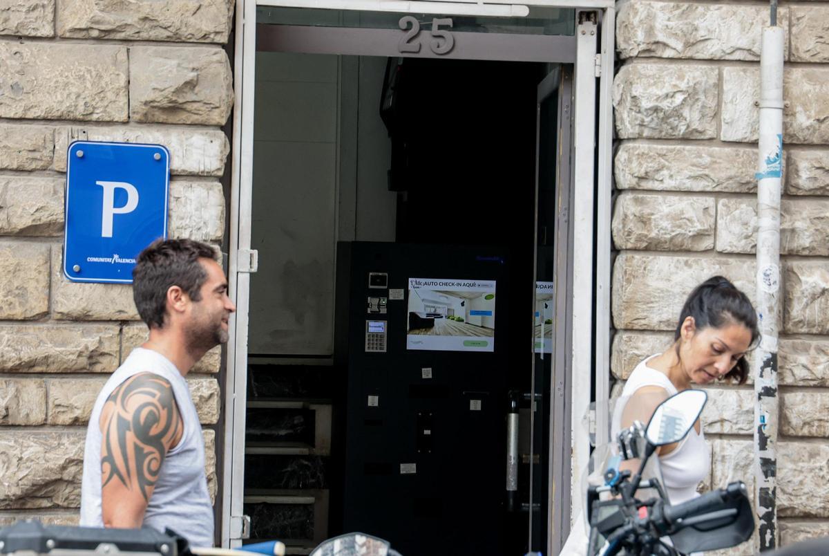 Dos personas pasan ante una puerta de una pensión en Alicante.