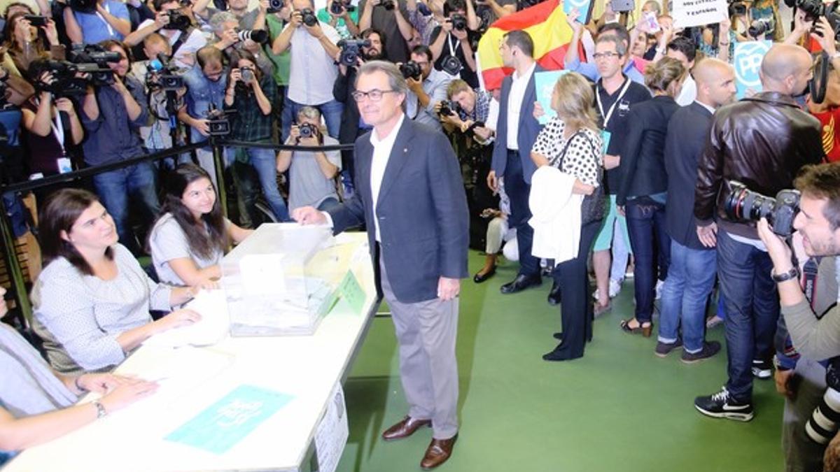 Artur Mas deposita su voto. Tras él, un joven ha desplegado una bandera española.