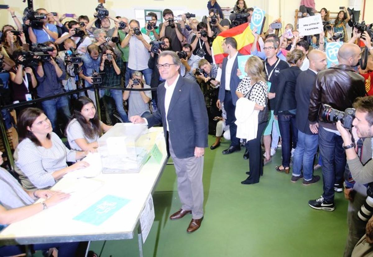 Artur Mas deposita su voto. Tras él, un joven ha desplegado una bandera española.