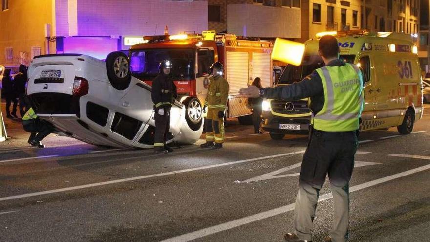 Un guardia civil dirige el tráfico frente al coche volcado ayer en pleno centro de Nigrán. // Jose Lores