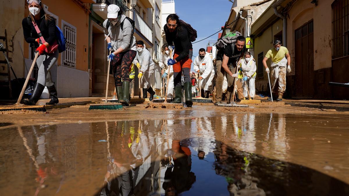 Decenas de personas limpiean las calles llenas de lodo por la DANA.