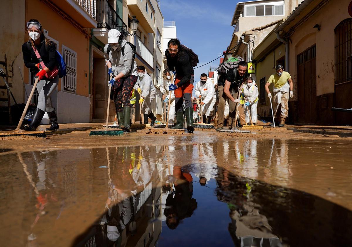 Decenas de personas limpiean las calles llenas de lodo por la DANA.