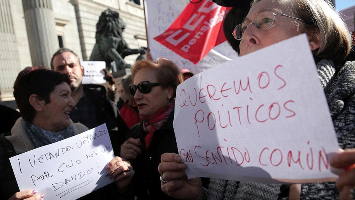 Dos mujeres muestran carteles contra los políticos, en una manifestación ante el Congreso para reclamar unas pensiones dignas, en el 2018