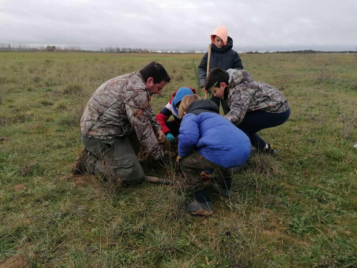 Niños y mayores colaboran en los trabajos de plantación en el coto