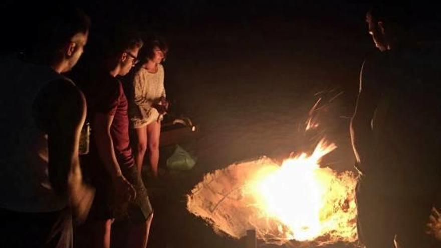 Un grupo de jóvenes rodea una de las hogueras encendidas en la costa de Sueca.