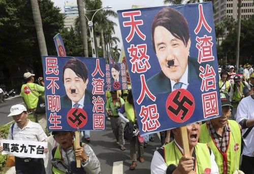 Activists holding placards with defaced images of Taiwan's President Ma Ying-jeou march along a street as they protest against Ma's policies in Taipei