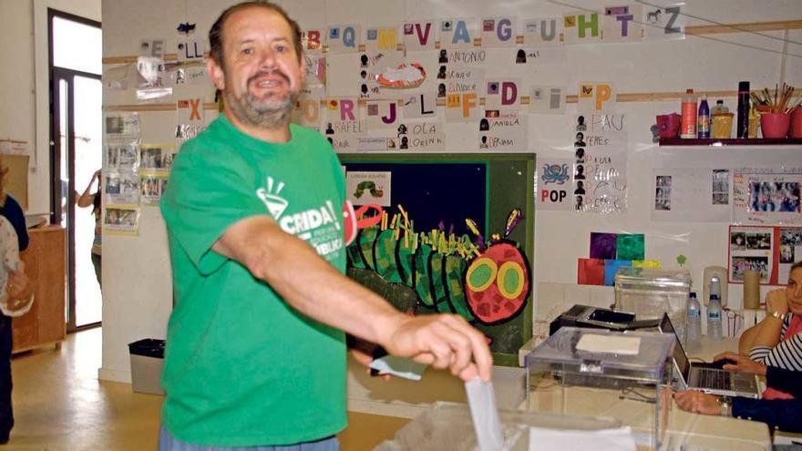 Un ciudadano, con la camiseta verde de Crida, introduce la papeleta en la urna electoral tras la comprobación de su DNI electrónico.