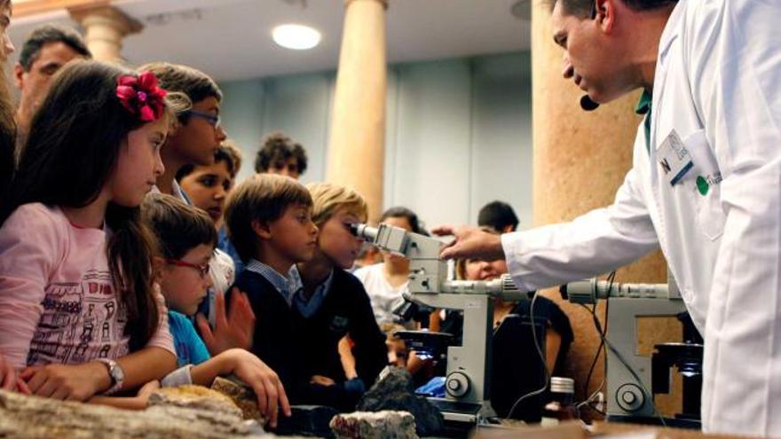 Varios niños, esperando para observar por un microscopio.