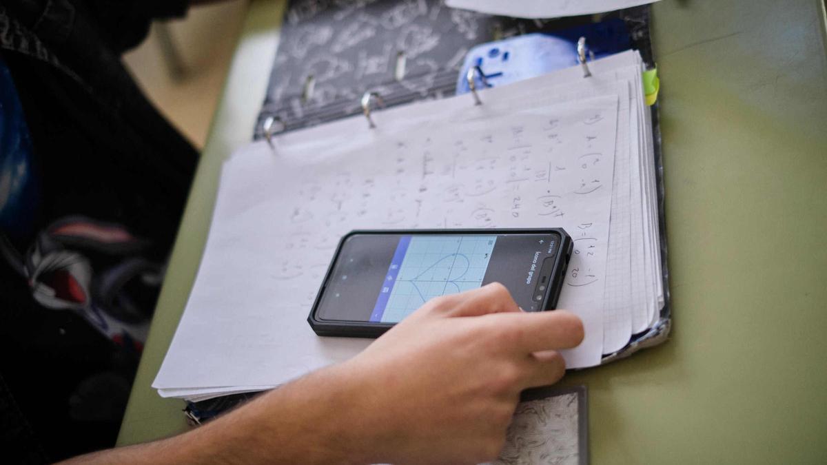 Un alumno utiliza el móvil durante una clase.