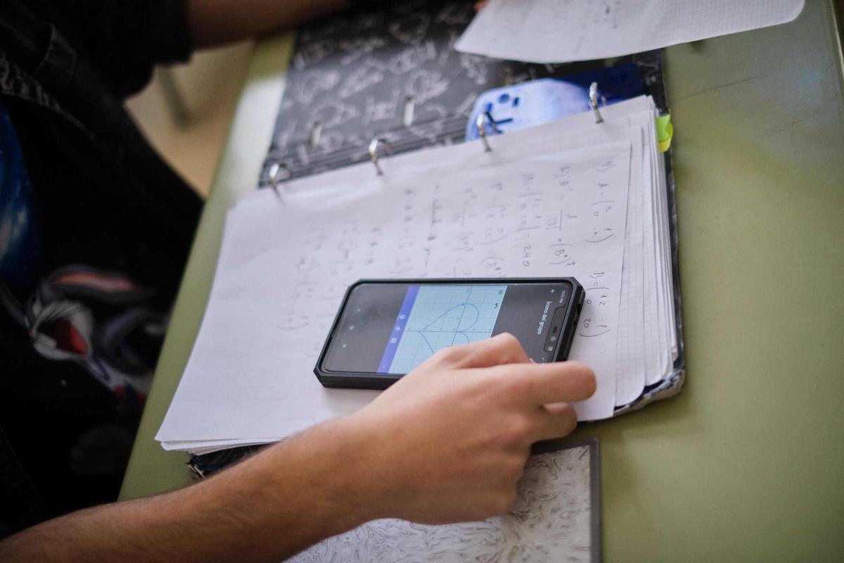 Un alumno utiliza el móvil durante una clase.