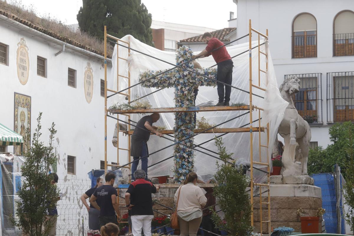 Montaje de la Cruz de Mayo del Resucitado, en la calle Conde de Priego, donde ha sido preciso protegerla con un plástico de la repentina lluvia.