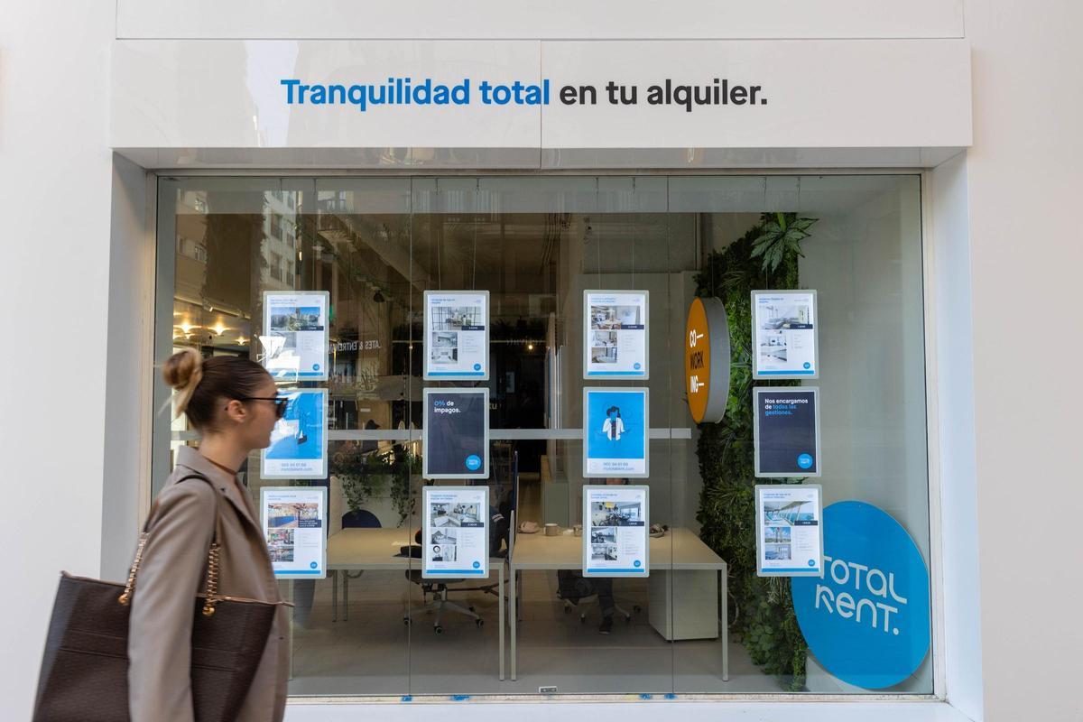 Una joven consultando los precios del alquiler en una inmobiliaria de Alicante.