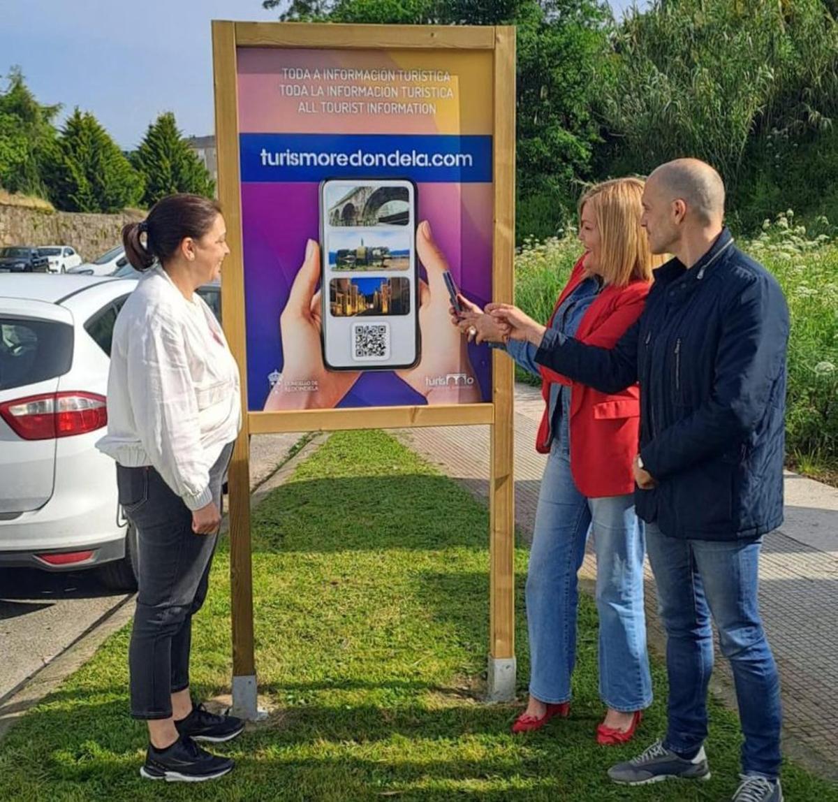 La alcaldesa redondelana, Digna Rivas (c.), y la edil de Cultura,  Rita Pérez, muestran uno de los nuevos QR de información turística. | C.R.