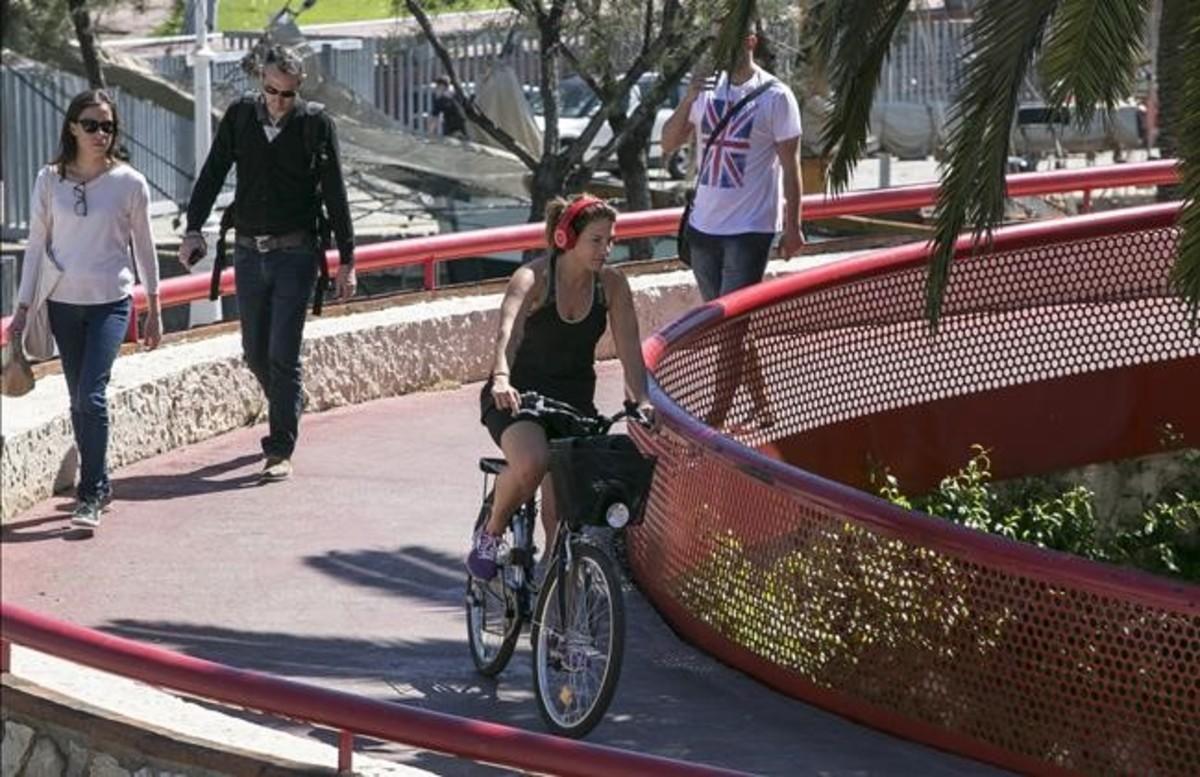 Una ciclista con auriculares circula por las pasarelas del Moll de la Fusta. 