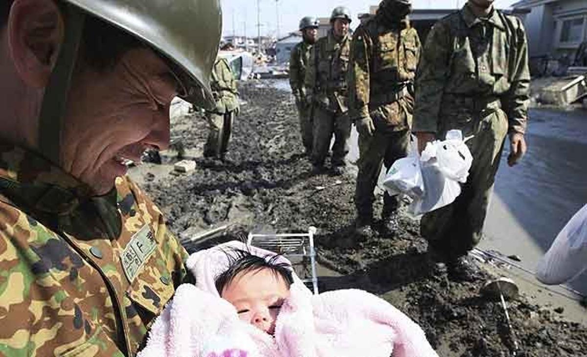 Un membre de la força de Defensa japonesa somriu després de rescatar una nena de quatre mesos a Ishinomaki (Japó), tres dies més tard del poderós terratrèmol que va afectar la costa est del país.