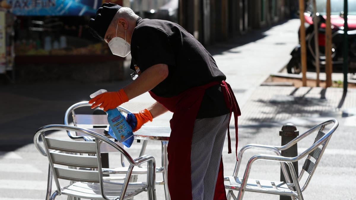 Un camarero limpia una mesa en una terraza.