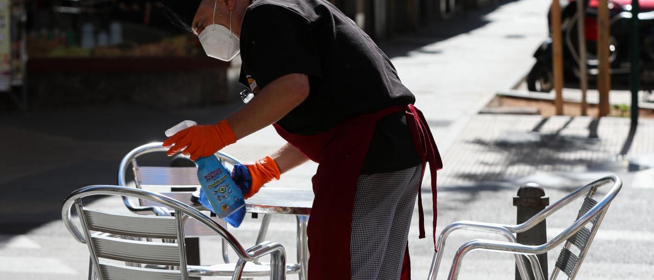 Un camarero limpia una mesa en una terraza.