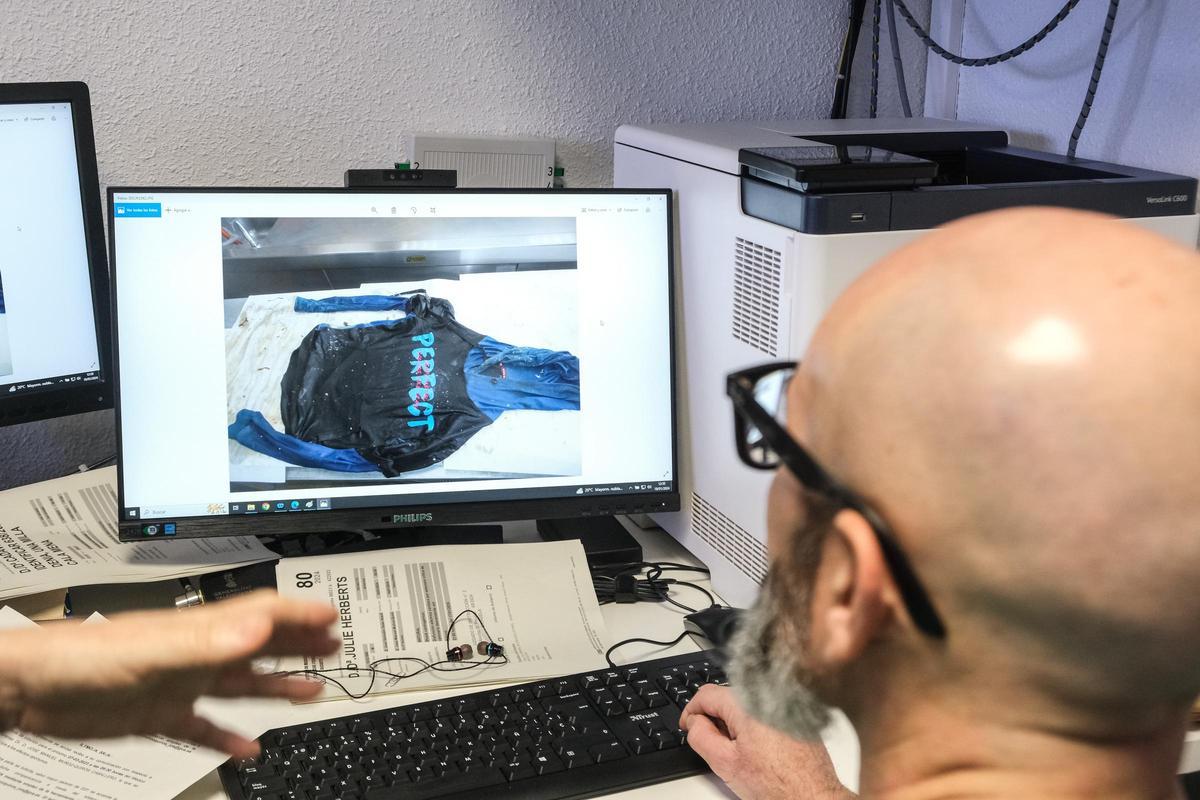 El forense José Manuel  Muñoz del Instituto de Medicina Legal de Alicante ante la foto de la  camiseta que llevaba un cadáver que bien podría ayudar para su identificación.