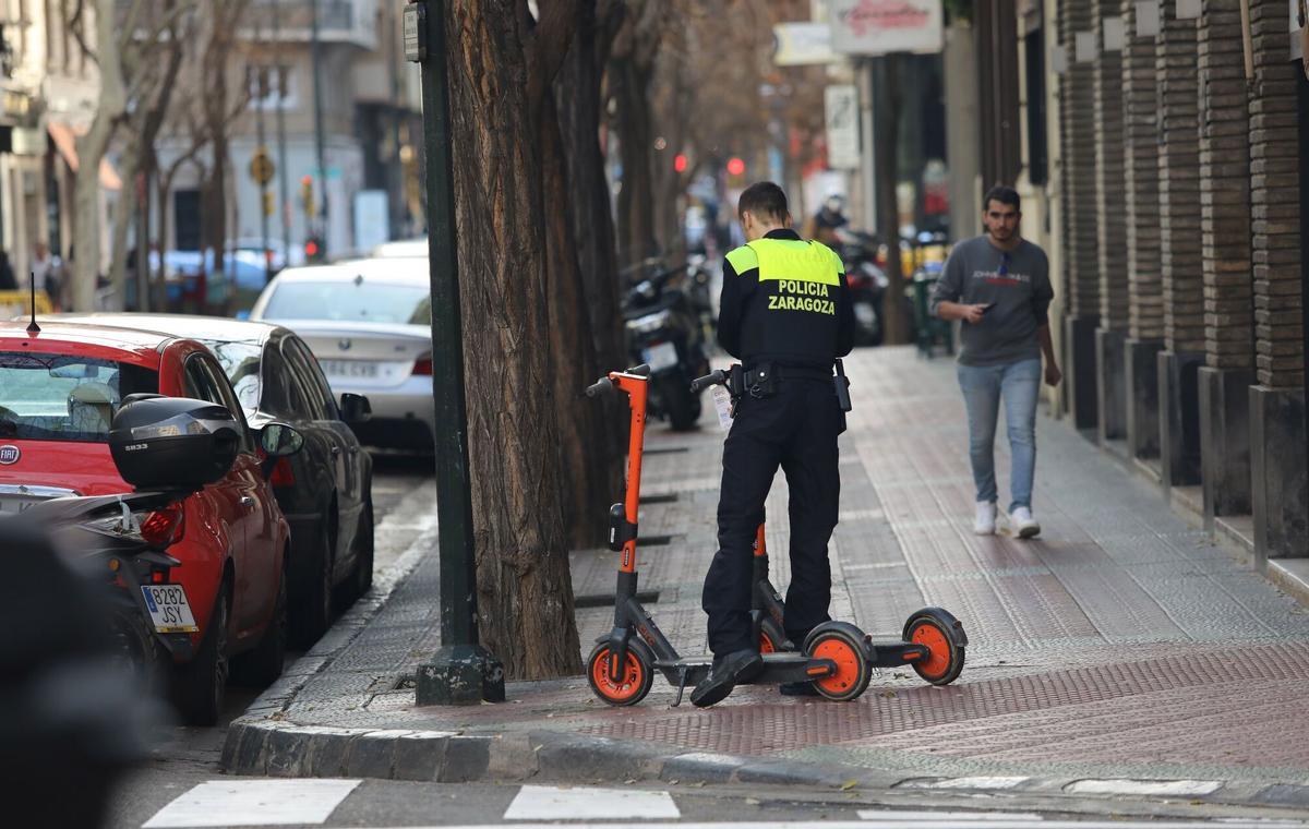 Un policía local de Zaragoza con dos patinetes eléctricos.