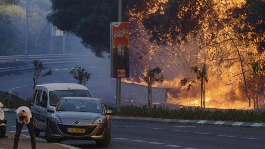 Un hombre se cubre la cabeza junto a un incendio forestal.