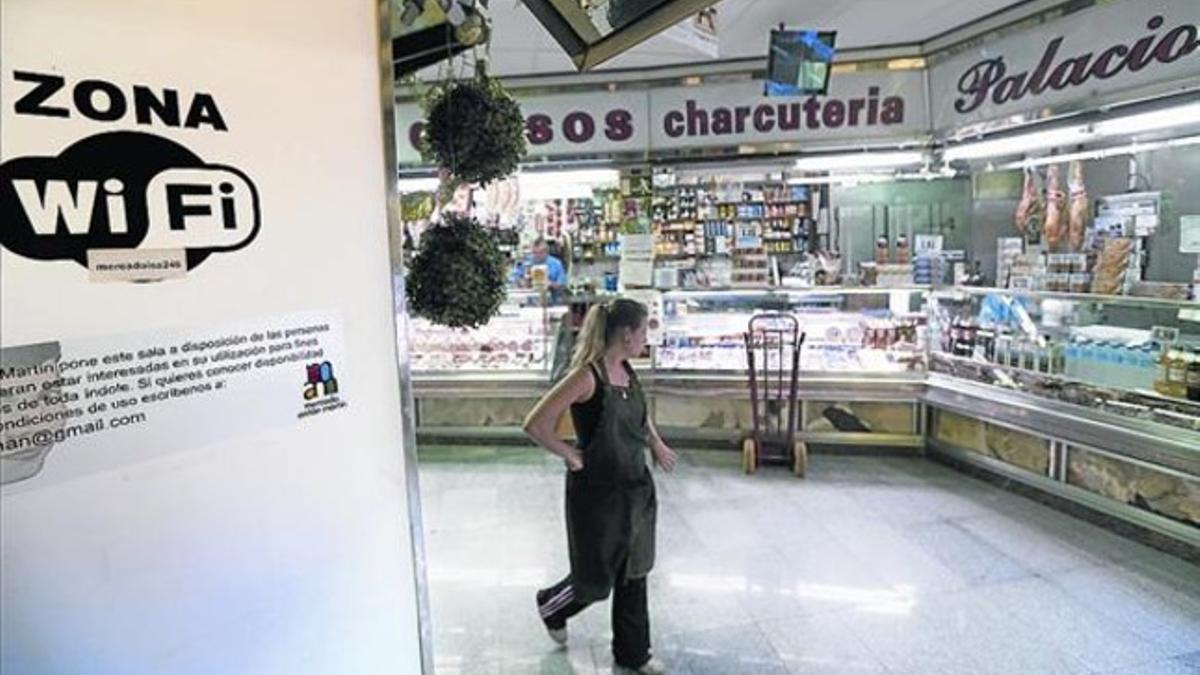 Una mujer pasa ante una zona wifi en el mercado de Antón Martín de Madrid.