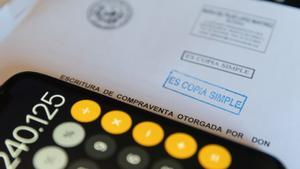 Archivo - Una calculadora y una escritura de compraventa de una hipoteca.