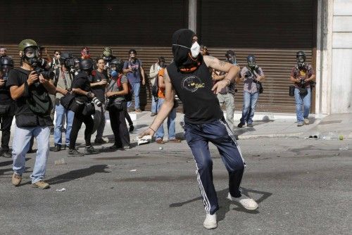 Press photographers encirle a protester as he throws a rock during a protest march by Greece's Communist party in central Athens at a 24-hour labour strike