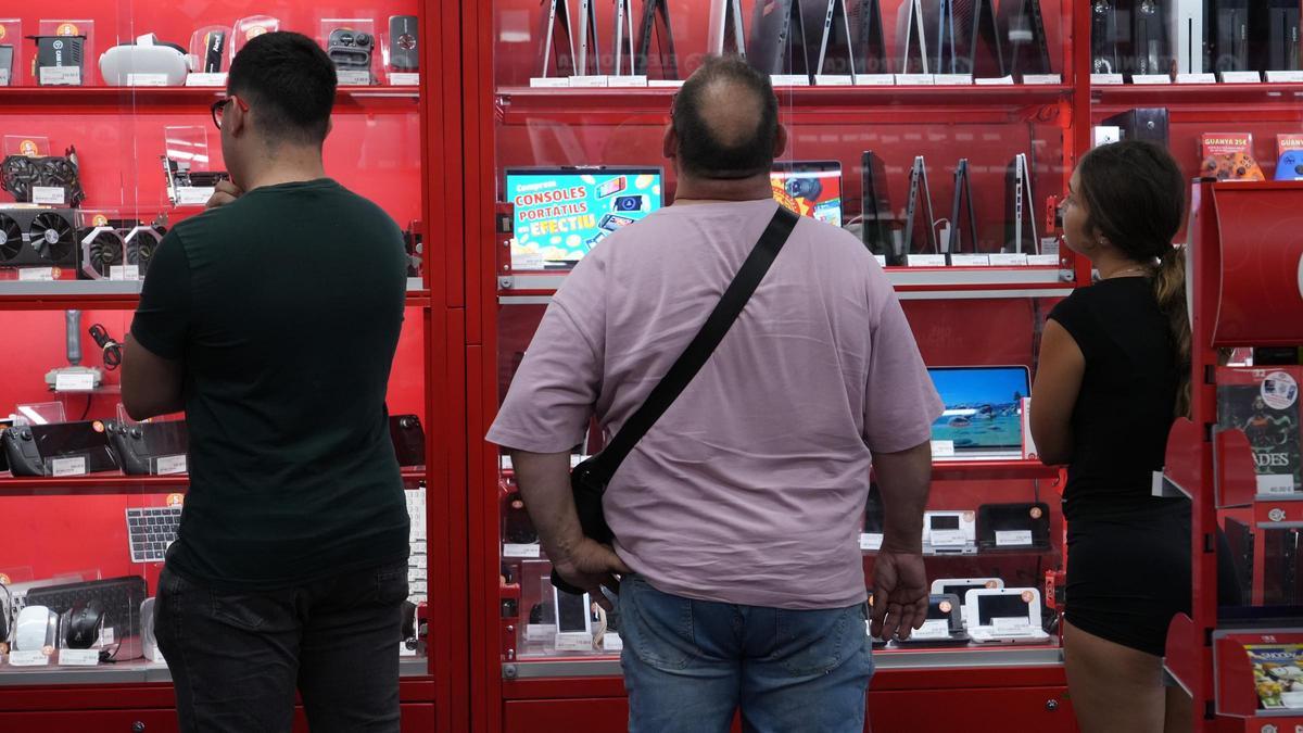 Un grup de persones en una botiga de videojocs i aparells tecnològics de Girona.