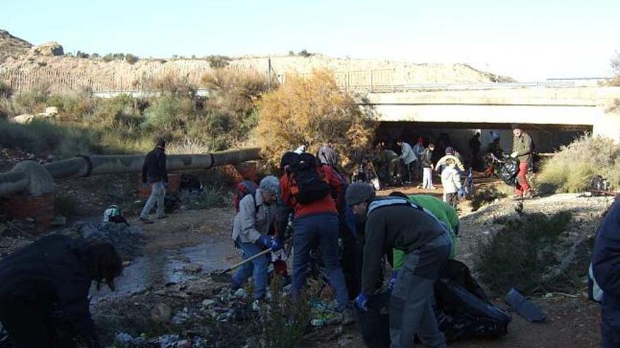 Un grupo de voluntarios limpia la gran cantidad de basura acumulada en el Barranco de la Sal.