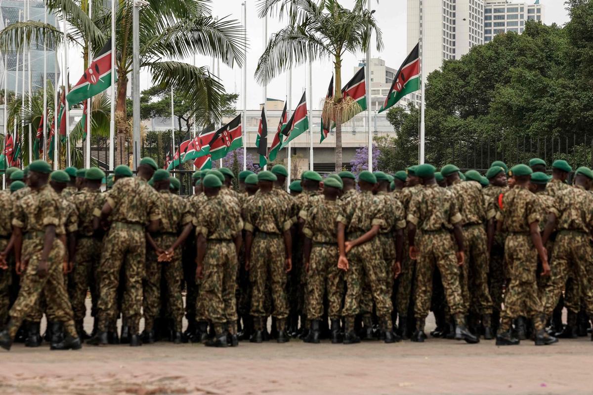TOPSHOT - Kenyan National Youth Service officers stand in front of Kenyan flags flying half mast in Nairobi on October 16, 2025  following the death of Kenyan opposition leader Raila Odinga at the age of 80 during a health visit to India. Kenyan opposition leader Raila Odinga has died at the age of 80 during a health visit to India, local police said on October 15, 2025. Odinga was the perennial opposition figure of Kenyan politics, running unsuccessfully for the presidency on five occasions, most recently in 2022. He remained a dominant force, able to rally huge numbers, particularly from his native western Kenya. (Photo by SIMON MAINA / AFP)